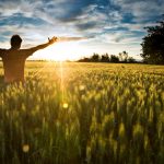 Man in sunshine, feeling happy and free with arms up in sky